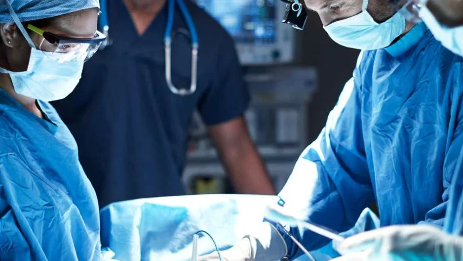 Photo of three medical professionals performing surgery 