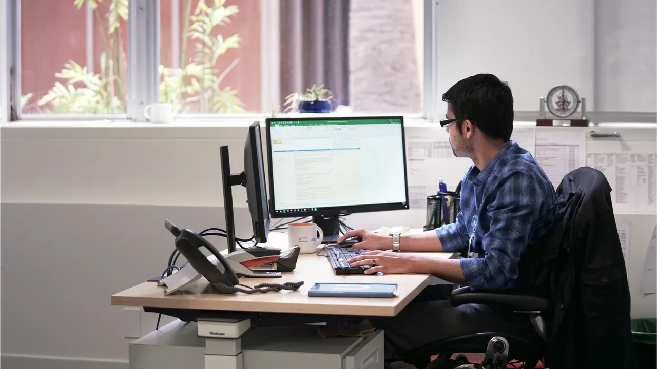 A person working at a desk with two computer monitors