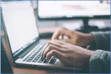 Image of a person typing on a laptop with grid