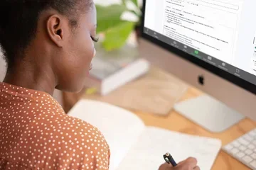 Woman writing notes at computer