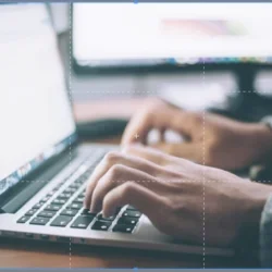 Image of a person typing on a laptop with grid