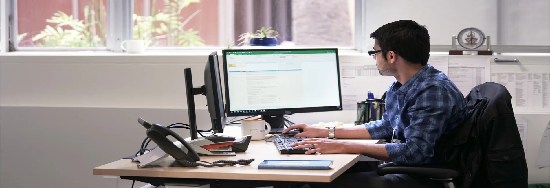 A person working at a desk with two computer monitors